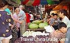 A free market in Wanxian county selling various fruits like watermelon, grape and apple.